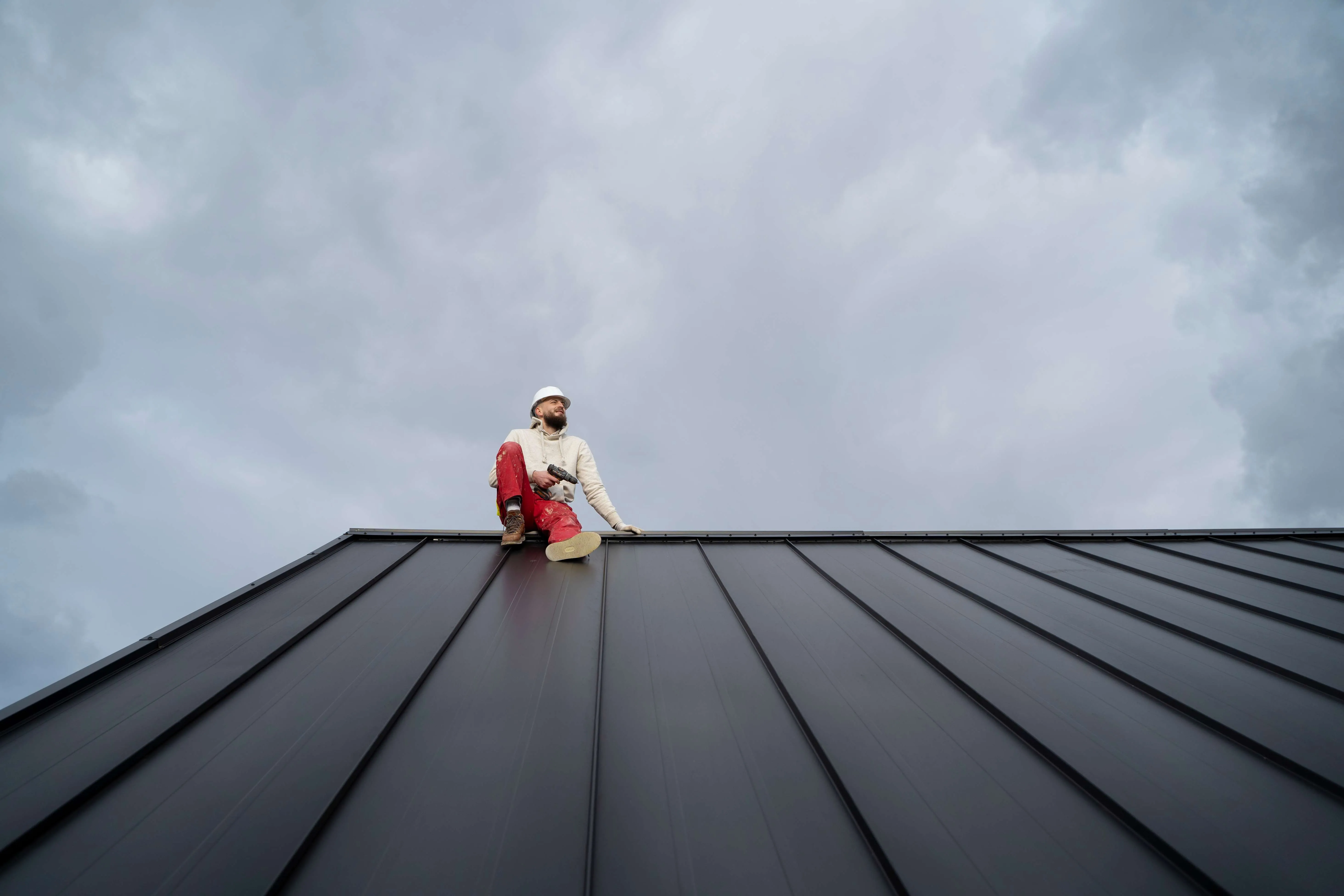 Professional roofer applying waterproofing protection on Qatar building with safety equipment
